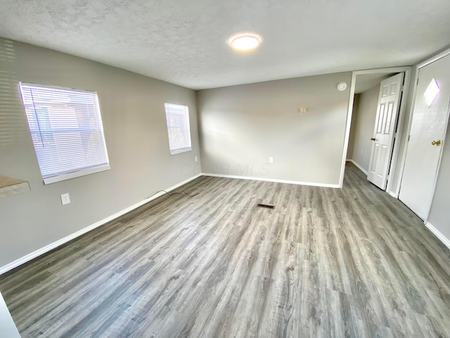 unfurnished room with light hardwood / wood-style flooring and a textured ceiling