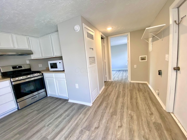 kitchen with gas range, white cabinetry, a textured ceiling, and light wood-type flooring