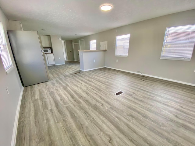 unfurnished living room with light hardwood / wood-style floors and a textured ceiling