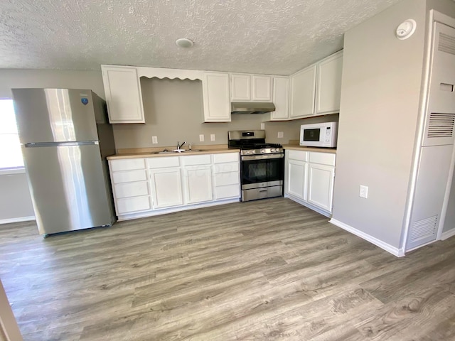 kitchen featuring appliances with stainless steel finishes, sink, white cabinets, and light wood-type flooring