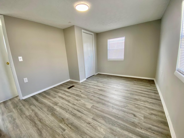 unfurnished bedroom featuring a closet, a textured ceiling, and light wood-type flooring