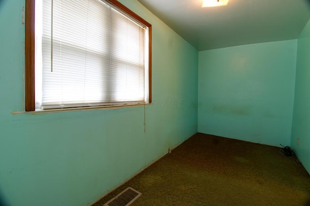 additional living space with dark colored carpet and visible vents