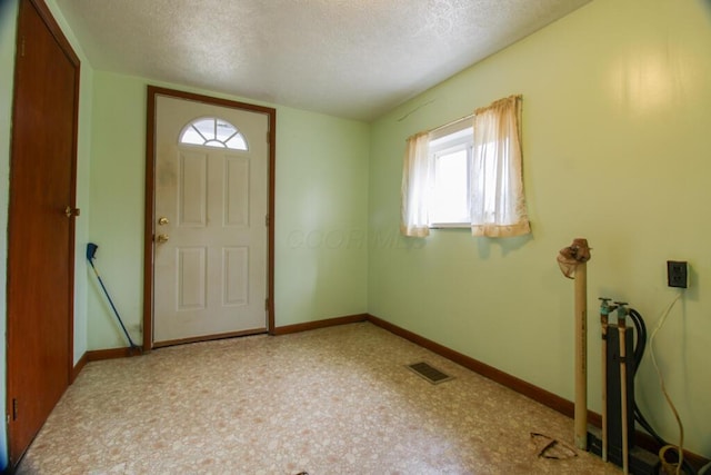 foyer featuring visible vents, a textured ceiling, and baseboards