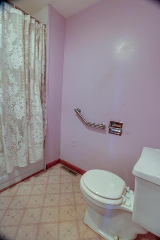 bathroom with toilet, baseboards, visible vents, and tile patterned floors