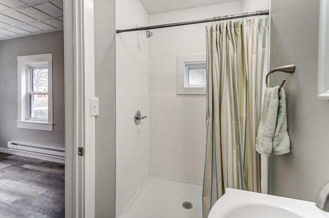 bathroom featuring a baseboard heating unit and curtained shower