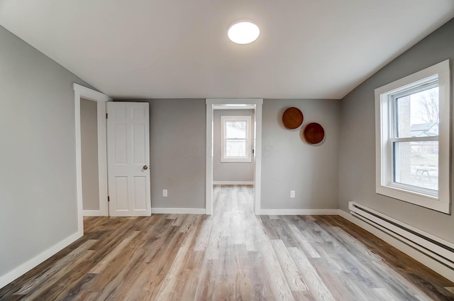 unfurnished room with baseboard heating and light hardwood / wood-style flooring