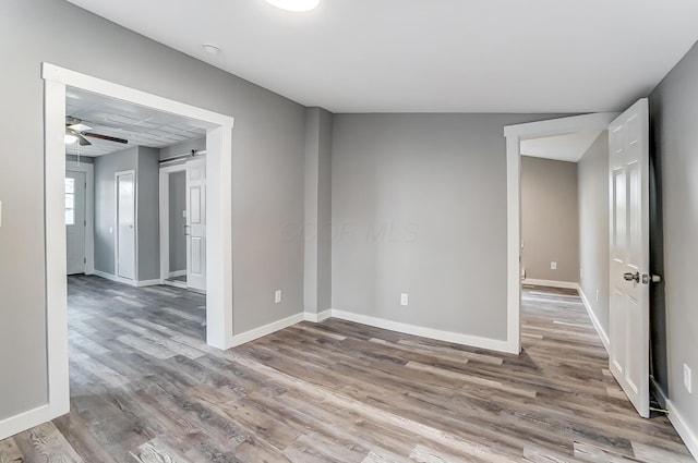 empty room with hardwood / wood-style floors, a barn door, and ceiling fan