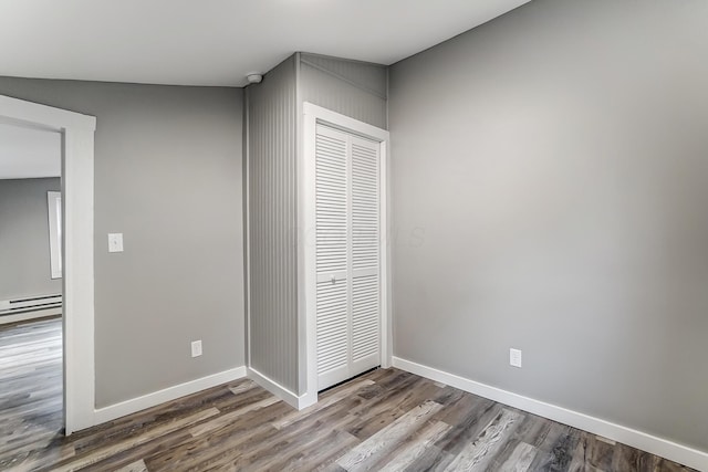 unfurnished bedroom with hardwood / wood-style flooring, a closet, and baseboard heating