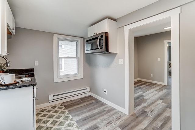 kitchen with white cabinetry, a baseboard radiator, and light wood-type flooring