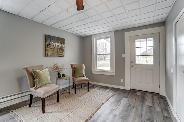 living area with hardwood / wood-style flooring and a baseboard heating unit