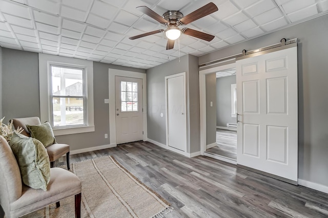 foyer entrance featuring a barn door, ceiling fan, and light hardwood / wood-style flooring