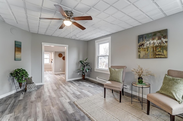 living area with ceiling fan, a baseboard radiator, and light wood-type flooring