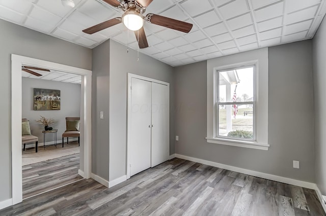 unfurnished bedroom featuring hardwood / wood-style floors, ceiling fan, and a closet