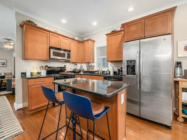 kitchen featuring a kitchen island, stainless steel appliances, ornamental molding, a kitchen bar, and light wood-type flooring