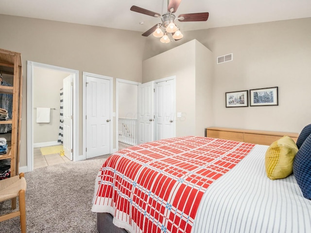 bedroom with ensuite bath, vaulted ceiling, multiple closets, ceiling fan, and light colored carpet