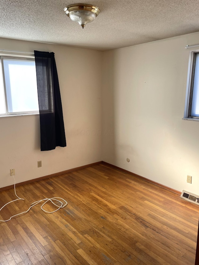 unfurnished room with wood-type flooring and a textured ceiling