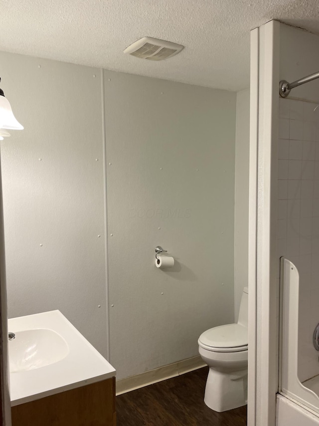 full bathroom featuring shower / tub combination, hardwood / wood-style floors, vanity, toilet, and a textured ceiling