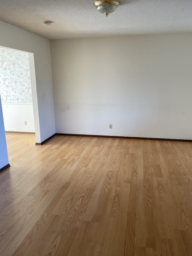 empty room with a textured ceiling and light wood-type flooring