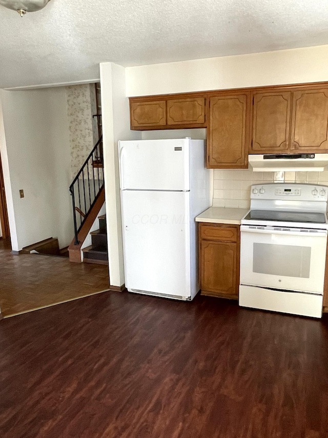 kitchen with backsplash, white appliances, dark wood-type flooring, and a textured ceiling