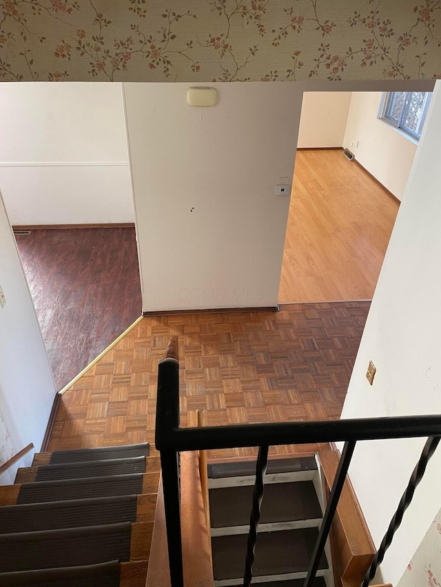 stairway featuring parquet flooring