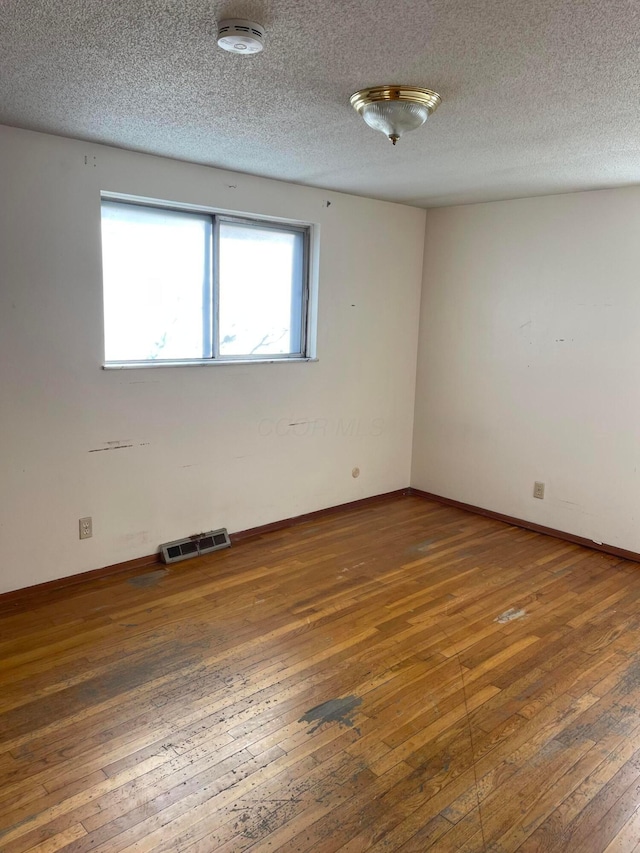 empty room with dark wood-type flooring and a textured ceiling