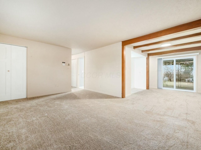 carpeted spare room with beam ceiling