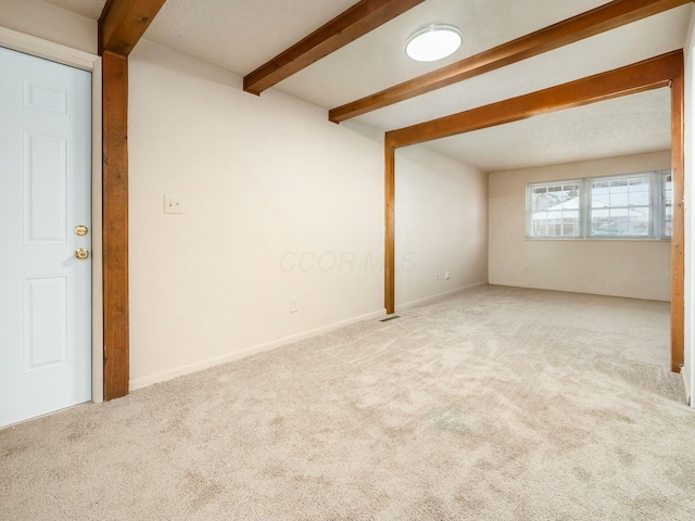 spare room with light carpet and beam ceiling