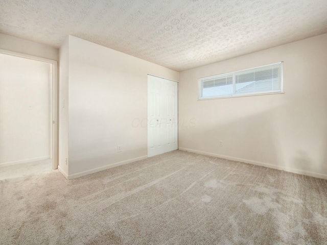 spare room with light colored carpet and a textured ceiling