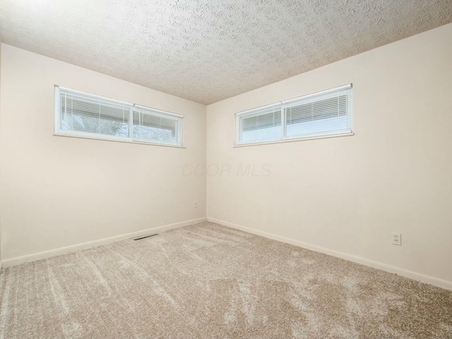 spare room with light carpet and a textured ceiling