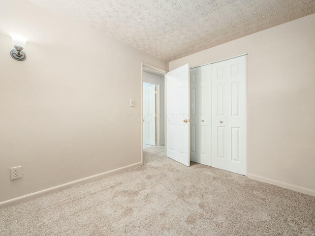 unfurnished bedroom featuring light colored carpet, a closet, and a textured ceiling