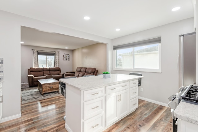 kitchen featuring wood-type flooring, a center island, white cabinets, and a barn door