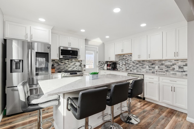 kitchen featuring white cabinetry, appliances with stainless steel finishes, and a kitchen breakfast bar