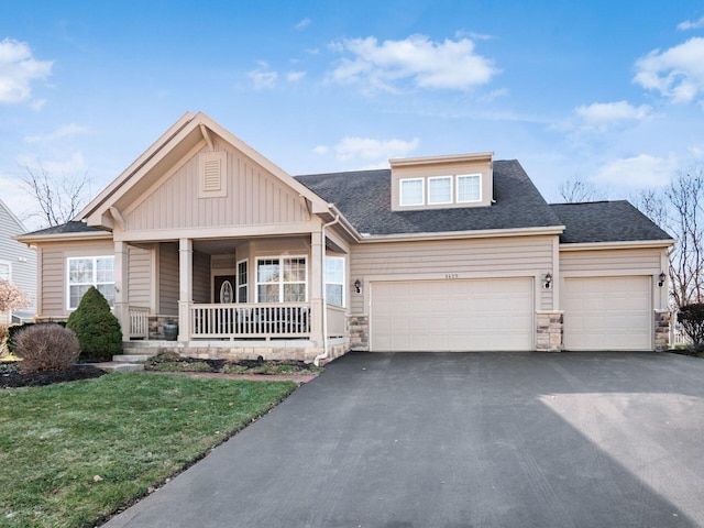 view of front facade featuring a garage, a front yard, and covered porch