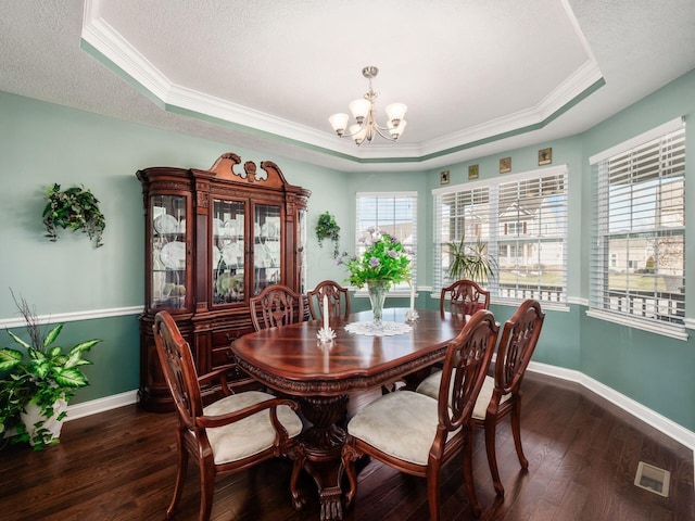 dining space featuring a tray ceiling, dark hardwood / wood-style flooring, and a notable chandelier