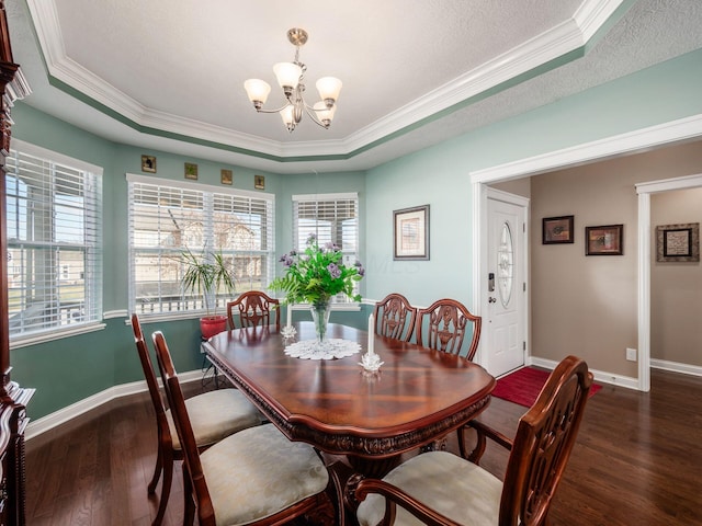 dining area with an inviting chandelier, crown molding, a textured ceiling, dark hardwood / wood-style floors, and a raised ceiling