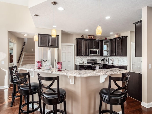 kitchen featuring stainless steel appliances, a breakfast bar area, pendant lighting, and decorative backsplash