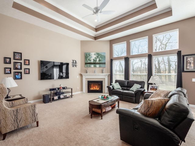 carpeted living room featuring crown molding, a towering ceiling, ceiling fan, and a tray ceiling