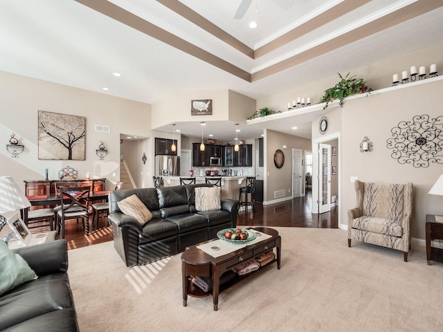 living room with crown molding, a raised ceiling, ceiling fan, and carpet flooring