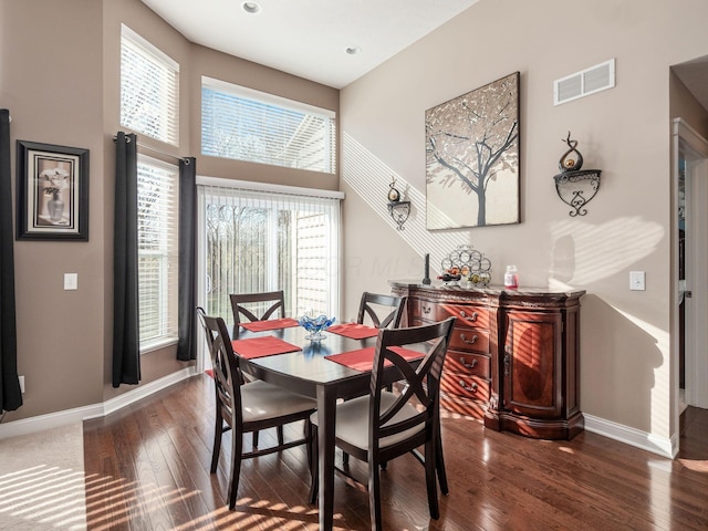 dining space with a towering ceiling and dark hardwood / wood-style flooring