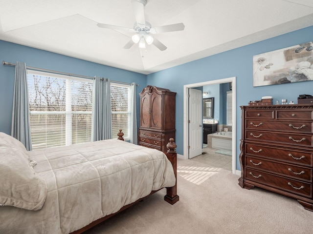 bedroom with ceiling fan, ensuite bath, and light carpet