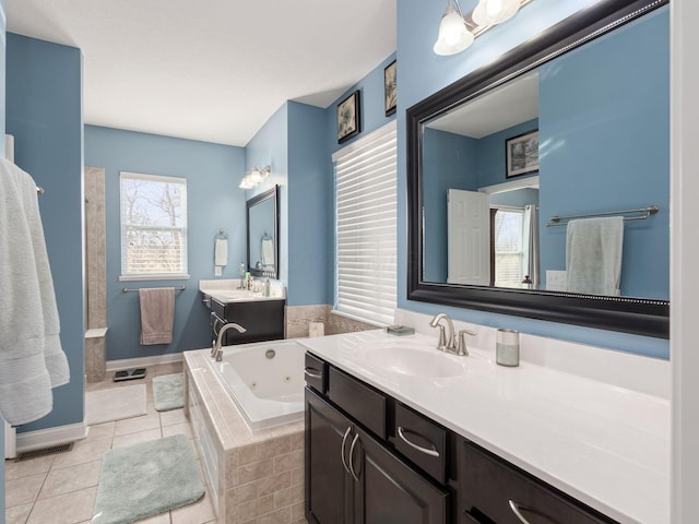 bathroom with tile patterned flooring, tiled tub, and vanity