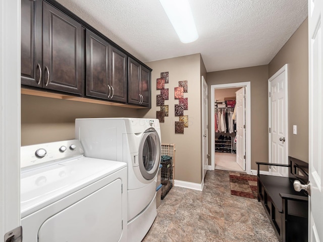 laundry area with independent washer and dryer, cabinets, and a textured ceiling