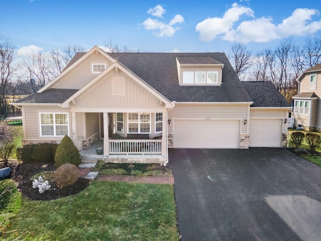 view of front of property featuring a garage, a front lawn, and a porch