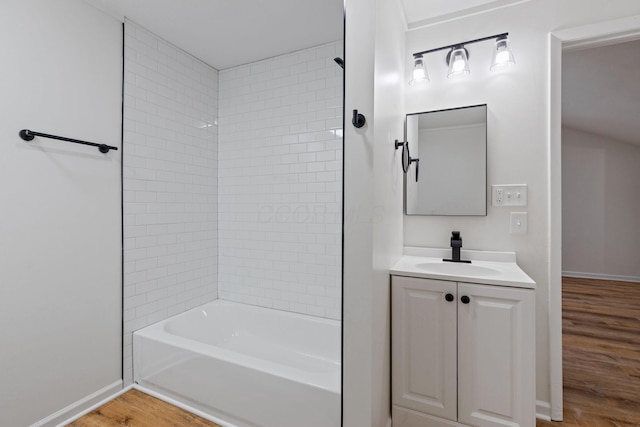 bathroom with hardwood / wood-style flooring, tiled shower / bath, and vanity