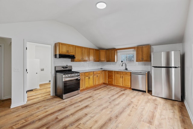 kitchen with lofted ceiling, sink, stainless steel appliances, light hardwood / wood-style floors, and backsplash