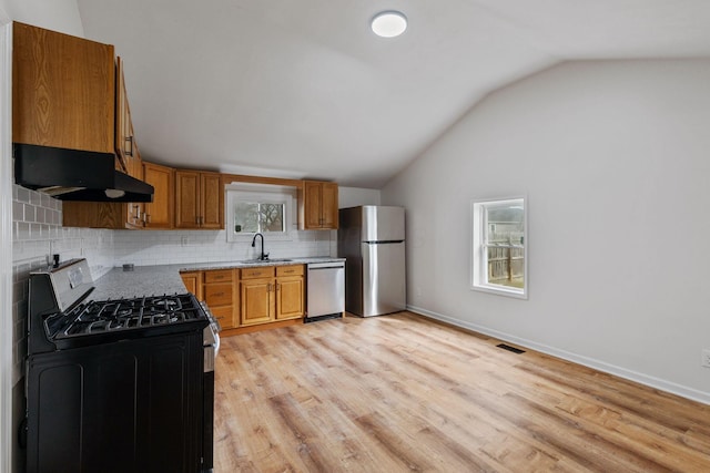 kitchen featuring sink, appliances with stainless steel finishes, light hardwood / wood-style floors, decorative backsplash, and vaulted ceiling