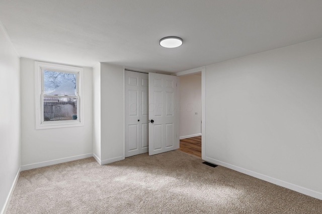 unfurnished bedroom with light carpet and a closet