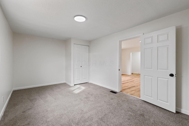 unfurnished bedroom featuring a closet, carpet, and a textured ceiling