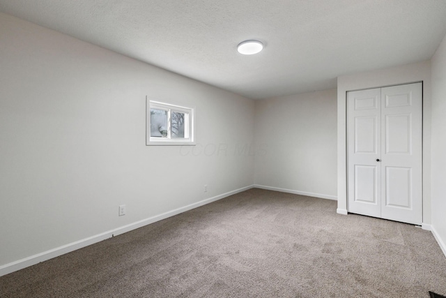 unfurnished bedroom with carpet floors, a closet, and a textured ceiling