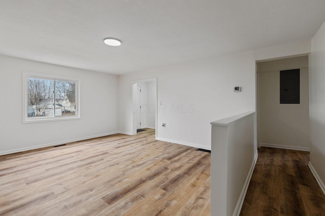 spare room with electric panel and light wood-type flooring